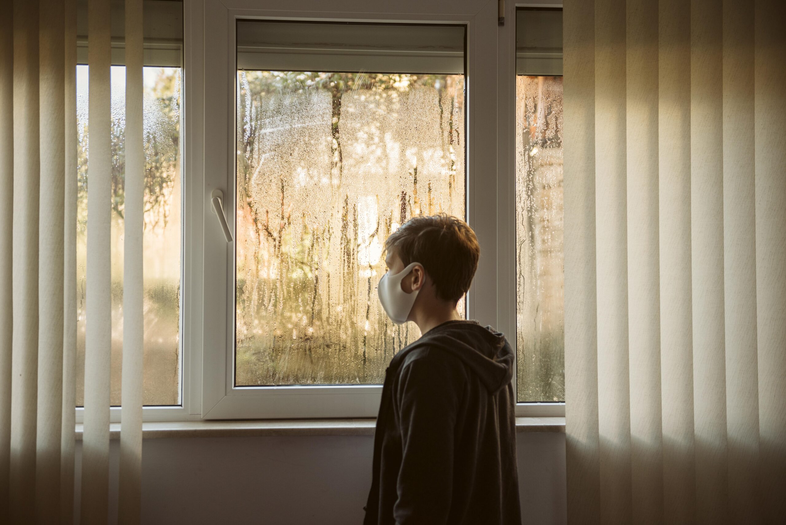 boy-with-face-mask-standing-windows